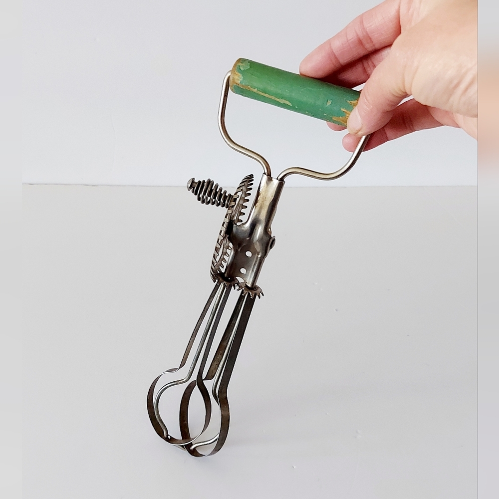 Antique metal egg beater with wooden handle.